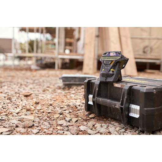 STANLEY FMHT1-77356 laserwaterpas op zwarte gereedschapskist, buiten bouwplaats, schuine vooraanzicht.