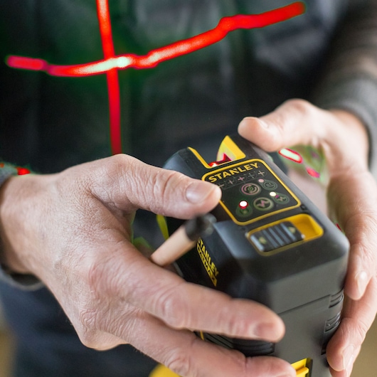 Foto van de STANLEY FMHT1-77414 laserwaterpas in hand, bedieningsknoppen en merk zichtbaar.