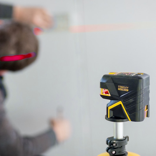 STANLEY FMHT1-77414 laserwaterpas op statief, rode lijn op muur geprojecteerd, close-up fotografie.