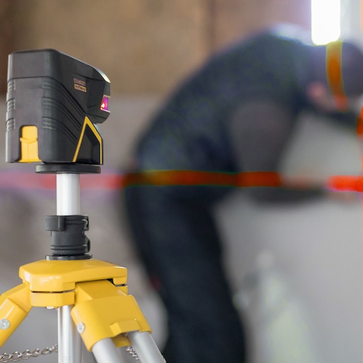 STANLEY FMHT1-77414 laser waterpas op statief, rode lijnen, binnenwerkruimte, zijaanzicht.