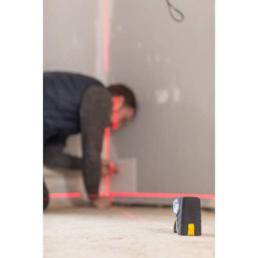 STANLEY FMHT1-77415 laserwaterpas projecteert rode lijnen op een muur tijdens werkzaamheden, product op de voorgrond.