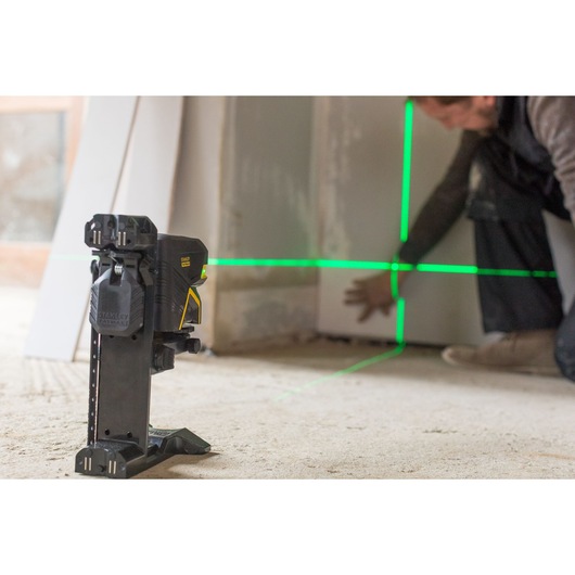 STANLEY FMHT1-77435 laserwaterpas projecteert groene lijnen op de muur tijdens bouw, zijaanzicht.