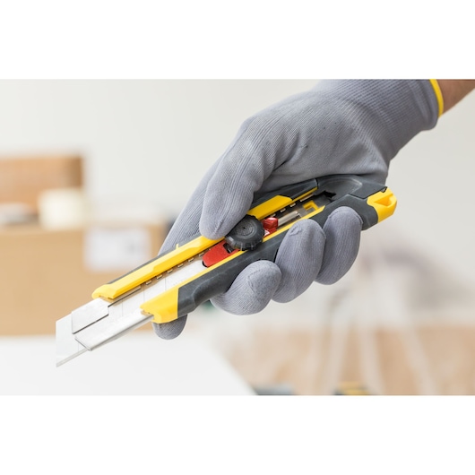 STANLEY FMHT10330-0 afbreekmes met geel-zwart handvat, vastgehouden in een gehandschoende hand.