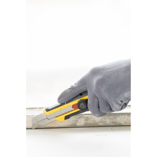 Foto van STANLEY FMHT10330-0 hobbymes in gehandschoende hand die langs een metalen geleider snijdt.