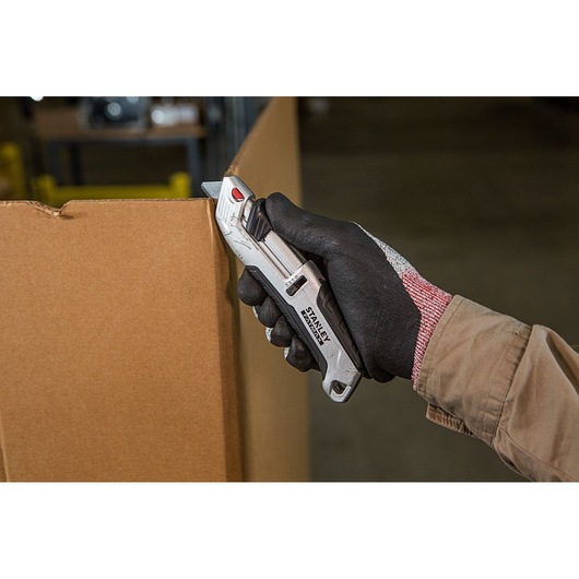 Stanley FMHT10367-0 mes snijdt karton, vastgehouden in een gehandschoende hand, product in gebruik.