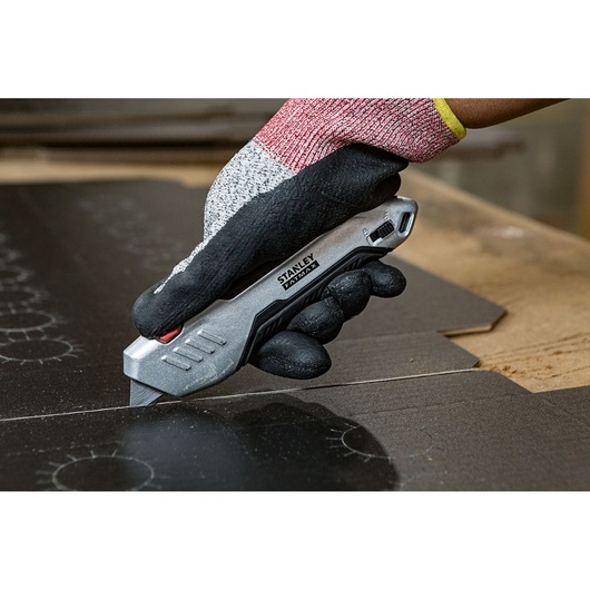 STANLEY FMHT10370-0 Stanleymes snijdt karton, vastgehouden door een gehandschoende hand, close-up foto.