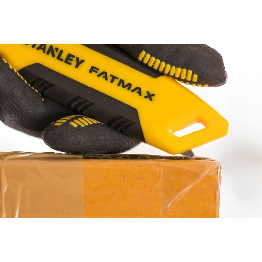 STANLEY FMHT10373-0 hobbymes met geel-zwarte handgreep, snijdt tape op kartonnen doos, close-up.
