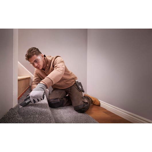 Couteau utilitaire STANLEY FMHT10500-0 utilisé sur un tapis, présenté lors d'une installation à domicile.