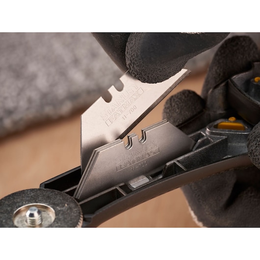 Lames utilitaires STANLEY FMHT10500-0 manipulées et rangées dans un porte-lames noir, photographie en gros plan.