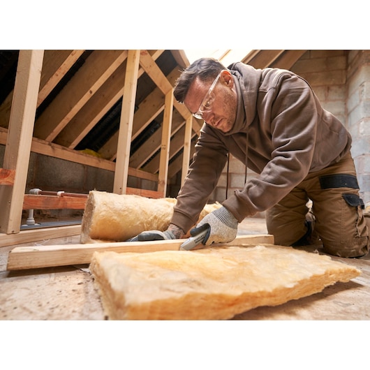 STANLEY FMHT10501-0 cutter utilisé pour couper un isolant dans un grenier, photo en gros plan de l’outil en action.