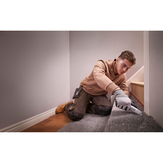 Photo d’un ouvrier utilisant un cutter STANLEY FMHT10501-0 pour couper de la moquette sur des escaliers.