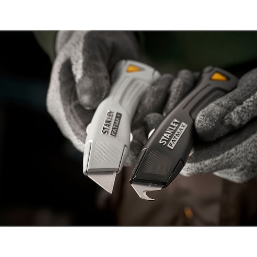 STANLEY FMHT10501-0 couteaux utilitaires, série FATMAX, gris et noir, tenus par des mains gantées, gros plan.