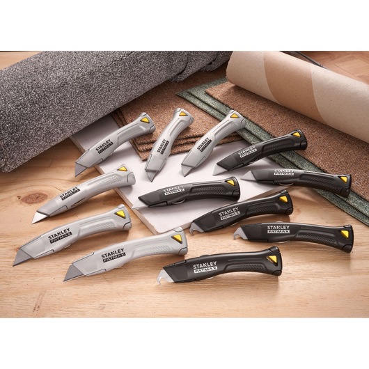 Couteaux utilitaires STANLEY FMHT10502-9 gris et noirs avec accents jaunes, disposés sur surface en bois.