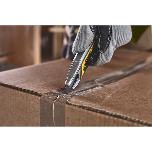 STANLEY FMHT10592-0 couteau utilitaire ouvrant une boîte en carton, vue rapprochée.