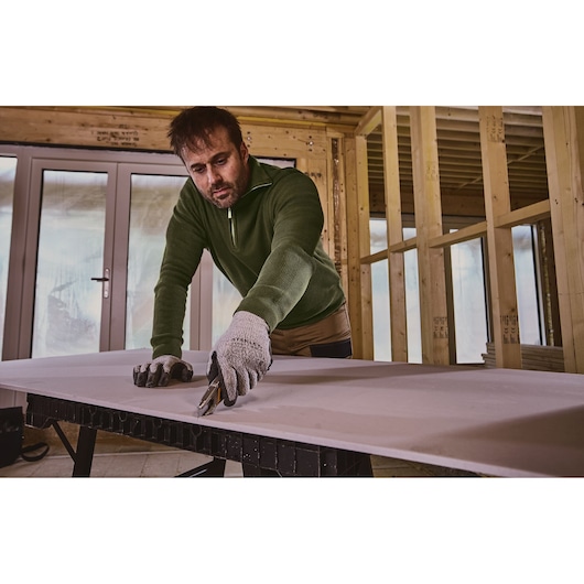 Stanley FMHT10592-0 utilisé pour couper du plâtre sur un établi dans un intérieur en construction.