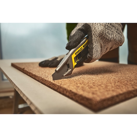 STANLEY FMHT10594-0 hobbymes snijdt een plaat, close-up actie met handschoenhand.