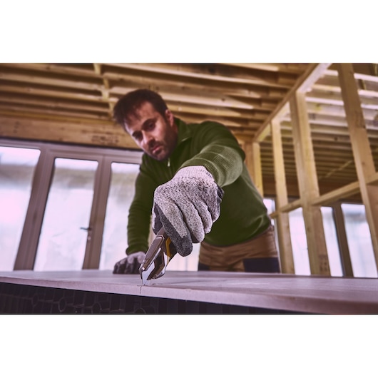 STANLEY FMHT10594-0 stanleymes snijdt plaatmateriaal, werknemer met handschoenen op bouwplaats.