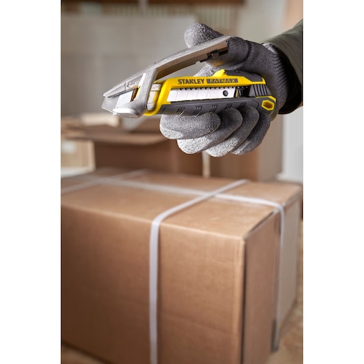 Stanley FMHT10594-0 stanleymes in een gehandschoende hand, opent een kartonnen doos.