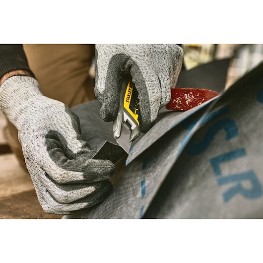 Foto van STANLEY FMHT10594-0 stanleymes dat stof snijdt, close-up met handschoenen.
