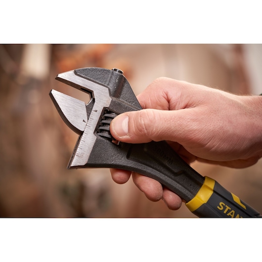 STANLEY FMHT13126-0 verstelbare moersleutel in hand, close-up van metalen bek en geel-zwarte handgreep.