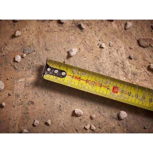 STANLEY FMHT33102 meetlint op stoffig beton met verspreide kleine stenen, close-up weergave.