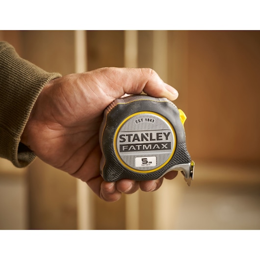 Foto van STANLEY FMHT38214-0 FATMAX rolmaat, 5m, zwart en geel, vastgehouden in hand.