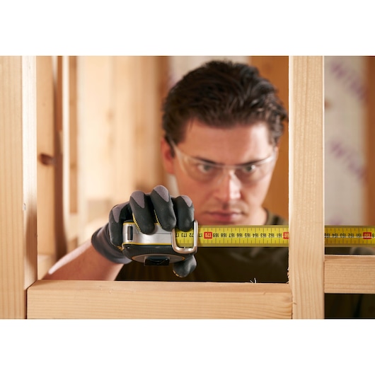 Foto van STANLEY FMHT38232-0 rolmaat in gebruik voor het meten van een houten frame tijdens de bouw.