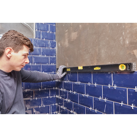 STANLEY FMHT42447-1 waterpas tegen blauwe tegelwand; bouwcontext.