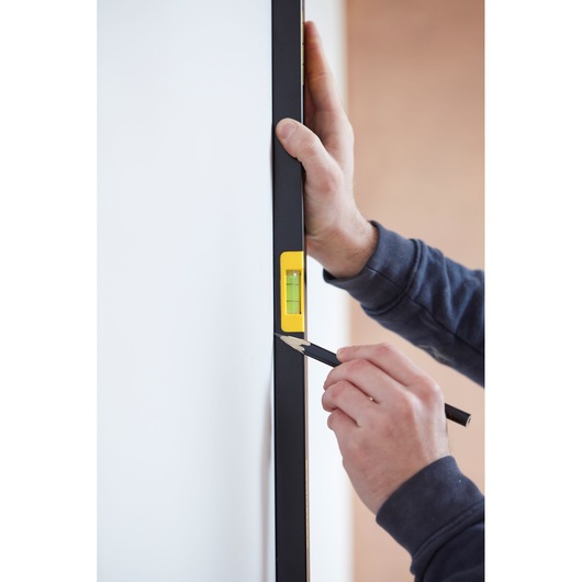STANLEY FMHT42559-1 waterpas in gebruik tegen een muur, persoon markeert met potlood.