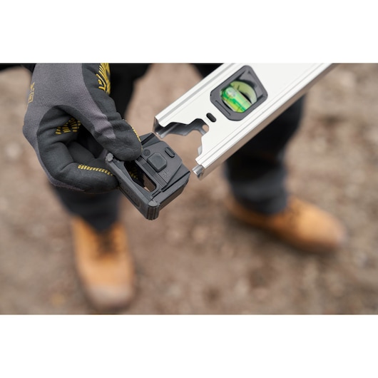 STANLEY FMHT43670-1 digitale waterpas vastgehouden door een gehandschoende hand buiten, close-up.