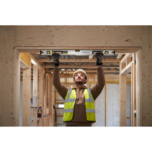 Foto van STANLEY FMHT43675-1 waterpas in gebruik op een houten deurkozijn tijdens de bouw.