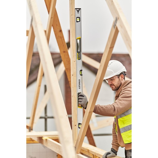 STANLEY FMHT43676-1 waterpas gebruikt door een bouwvakker op een houten constructiewerkplaats.