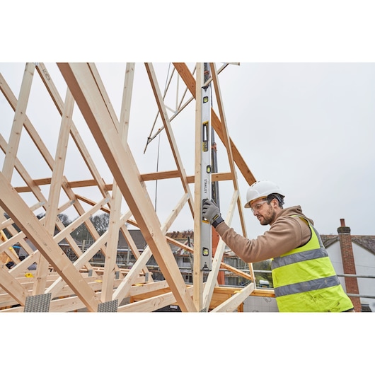 STANLEY FMHT43676-1 waterpas gebruikt door werknemer op houten frame op bouwplaats.