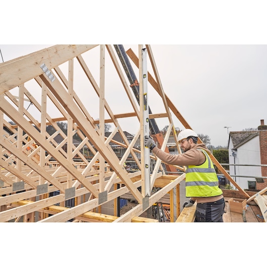 STANLEY FMHT43678-1 waterpas gebruikt door een bouwvakker op houten dakconstructie, buitenlocatie.