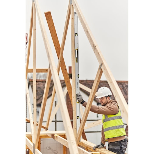 STANLEY FMHT43679-1 waterpas wordt verticaal gebruikt door een arbeider op een houten dakconstructie op bouwplaats.