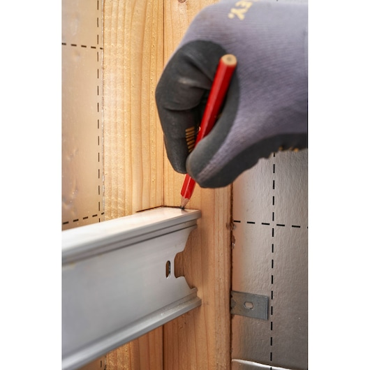 Stanley FMHT43679-1 fotografie van een gehandschoende hand die hout markeert naast een metalen rail bij bouw.