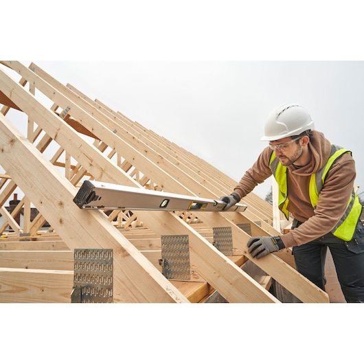 Foto van STANLEY FMHT43680-1 waterpas gebruikt op een houten dakconstructie tijdens de bouw.