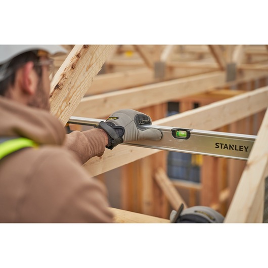 Stanley FMHT43680-1 waterpas gebruikt door werker op bouwplaats, focus op gereedschap en houten frame.