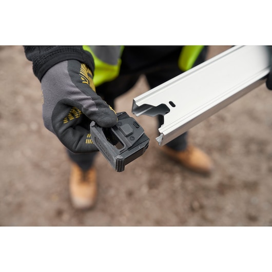 STANLEY FMHT43680-1 gereedschapscomponent vastgehouden door gehandschoende hand bij aluminium rail, close-up buiten.