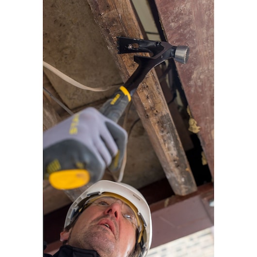 Marteau STANLEY FMHT51367-2 utilisé en construction, gros plan sur tête de frappe et manche noir.