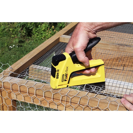 STANLEY FMHT6-70411 agrafeuse fixant un grillage sur un cadre en bois à l'extérieur.