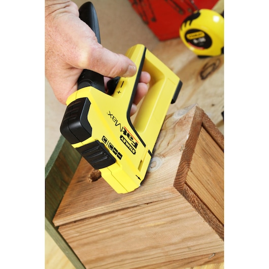 STANLEY FMHT6-70411 agrafeuse utilisée sur bois, jaune et noir, angle rapproché, main tenant l’outil.