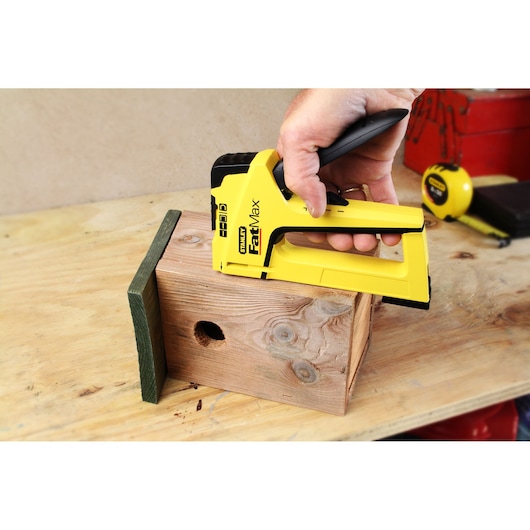 Photo de l'agrafeuse STANLEY FMHT6-70411 fixant des pièces en bois sur un établi.