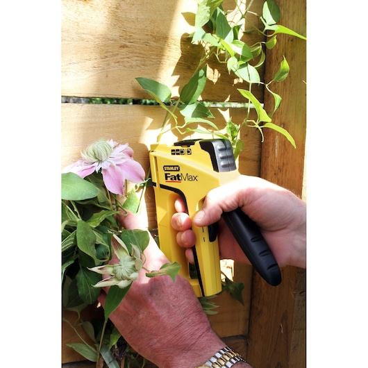 Photo de l'agrafeuse STANLEY FMHT6-70411 fixant une tige de fleur sur une planche en bois.