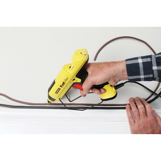 STANLEY FMHT6-70418 pistolet à colle FastMax jaune utilisé pour installer des câbles sur un mur.