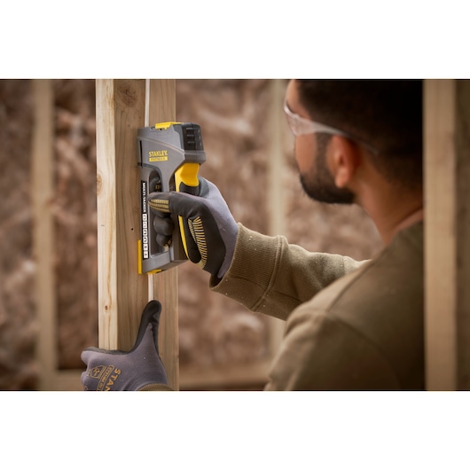 STANLEY FMHT6-70868 agrafeuse utilisée sur cadre en bois, photo rapprochée de l'outil et du gant.