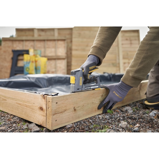 Agrafeuse multifonctions STANLEY FMHT6-70868 utilisée sur une jardinière en bois en extérieur.