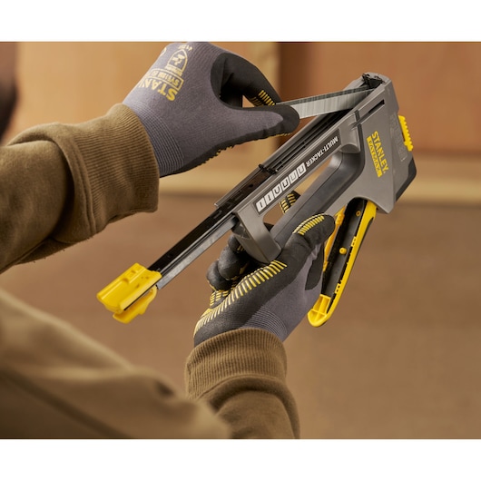 Stanley FMHT6-70868 multi-tacker chargé avec des agrafes par des mains gantées dans un atelier.
