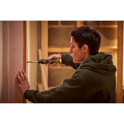 Personne utilisant un tournevis STANLEY FMHT62692-0 sur un cadre de porte, produit en utilisation, intérieur.