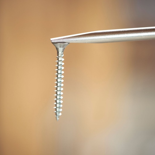 Dichtbij van een schroevendraaierpunt die contact maakt met een metalen schroef.